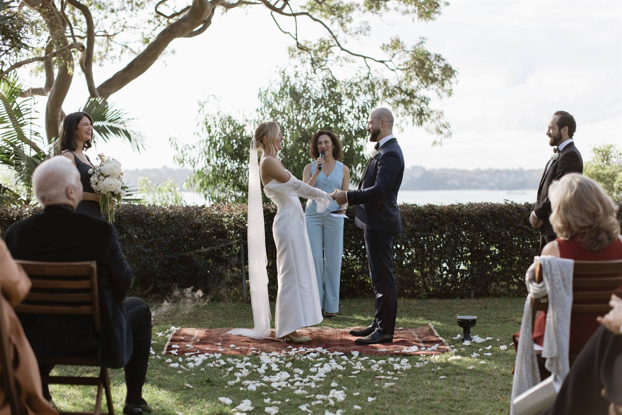 A bride and groom holding hands at an outdoor waterfront wedding ceremony